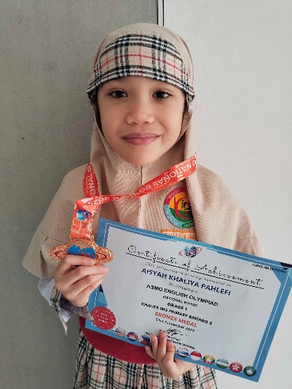 Aisyah Khaliya Pahlefi holding her ASMO English Olympiad bronze medal