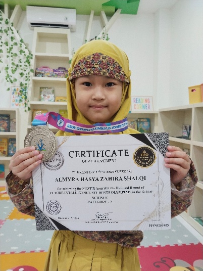 Almyra Hasya Zahira Shalqi holding her FISO International gold certificate