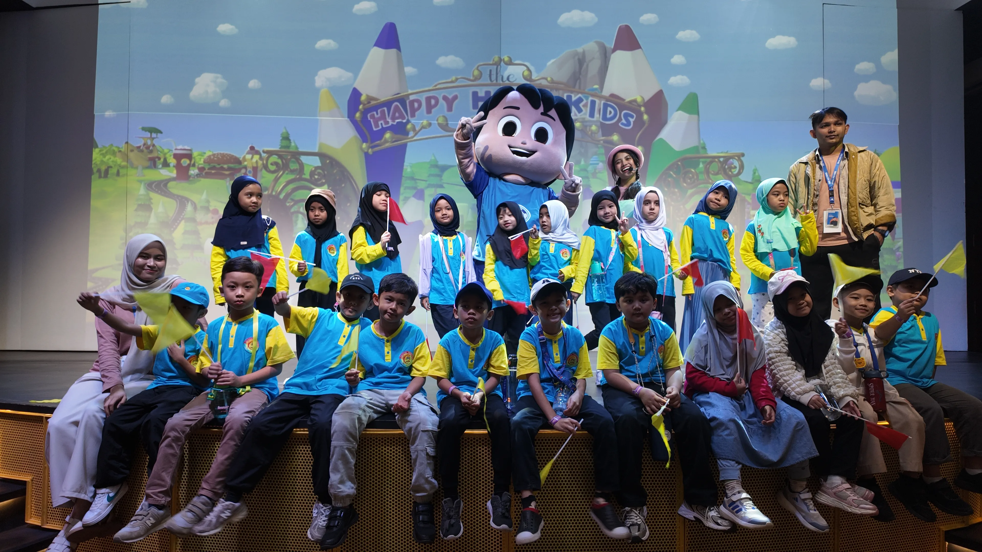 Students posing with a mascot on stage during a Happy Holiday Kids field trip