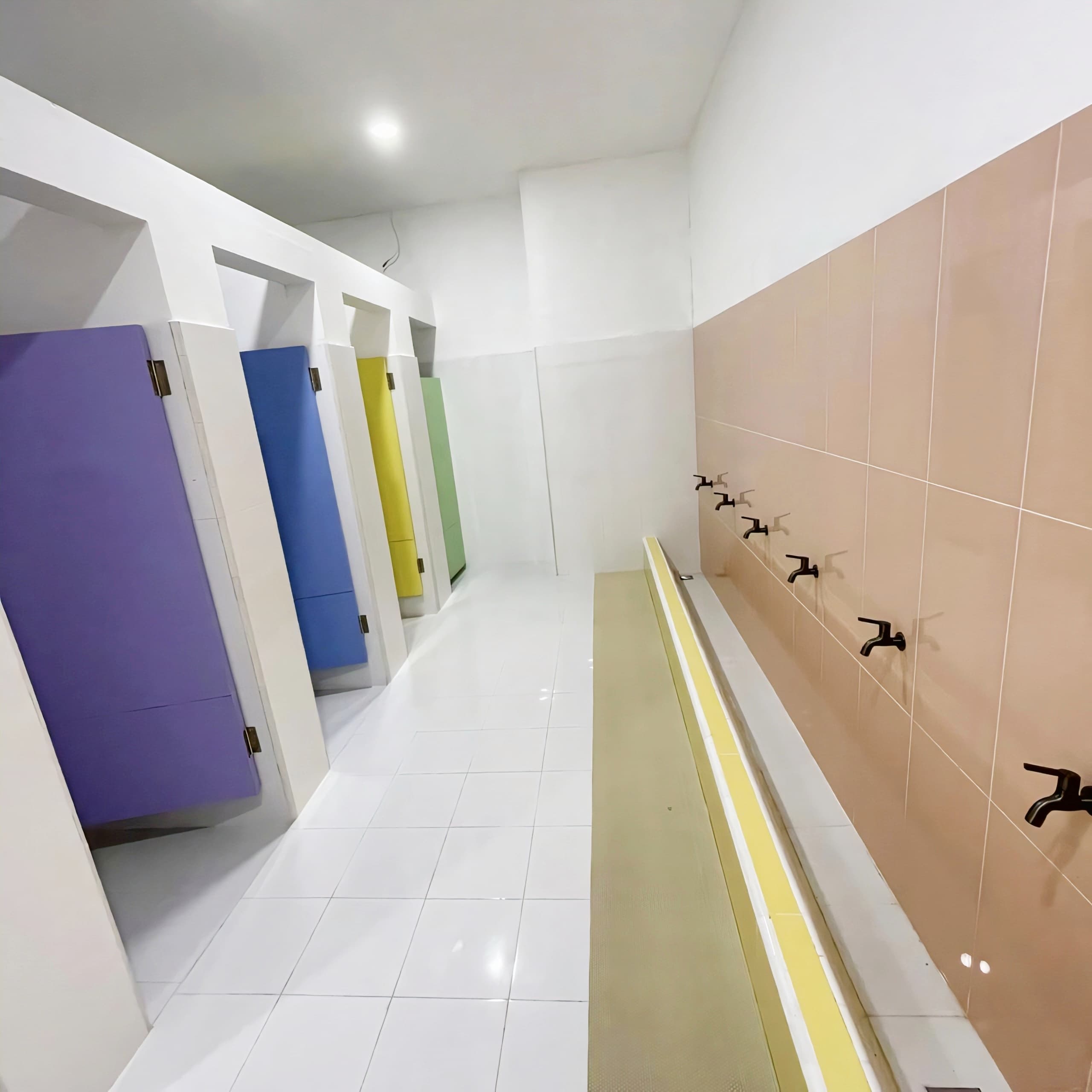 Boys' toilet with colourful stall doors and a row of taps