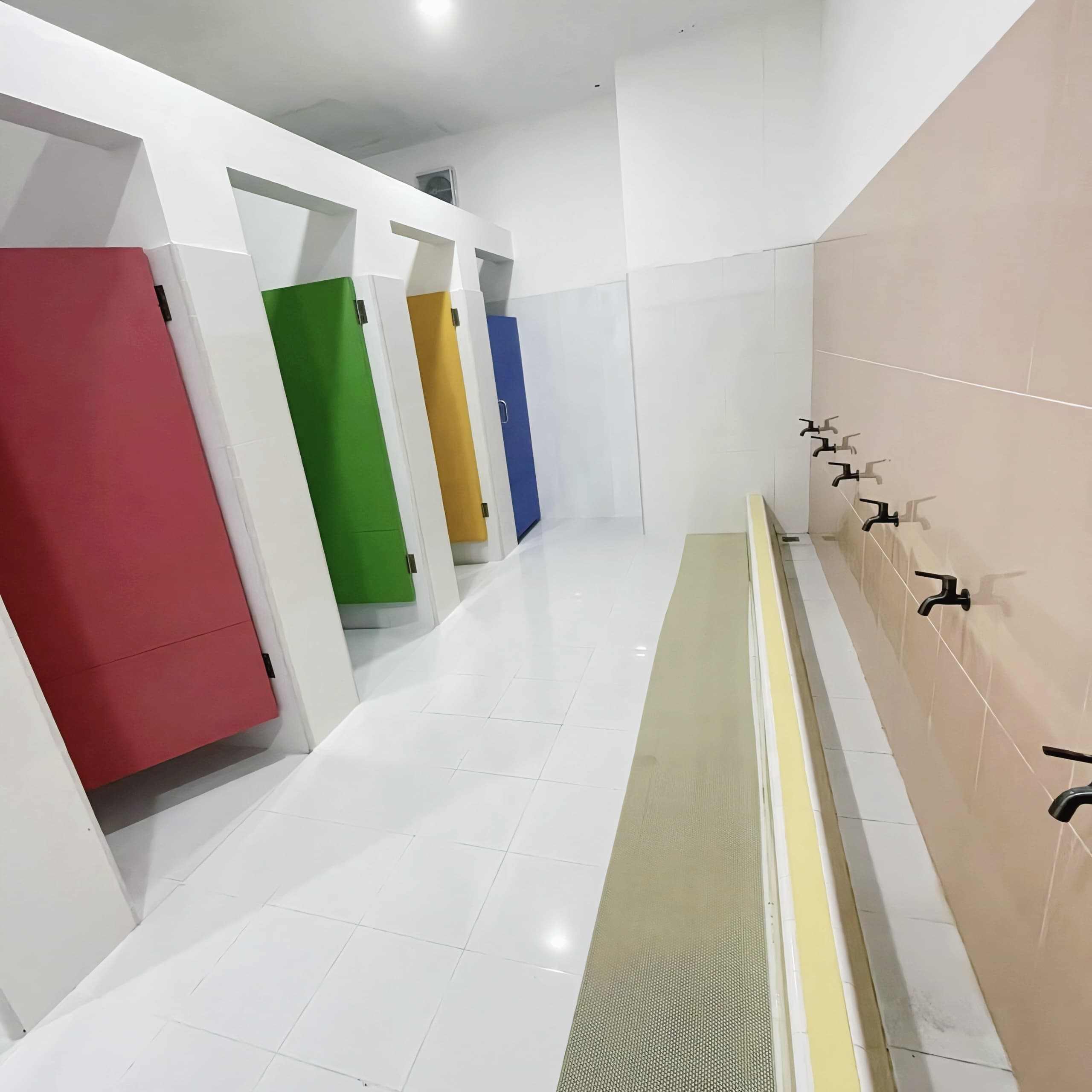 Girls' toilet with colourful stall doors and a row of taps